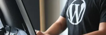 person at computer wearing a shirt with a wordpress logo