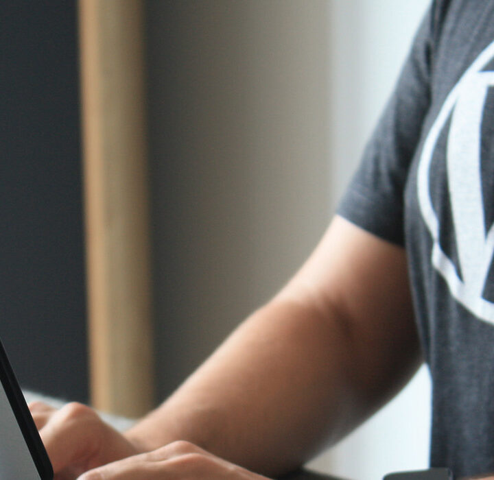 person at computer wearing a shirt with a wordpress logo